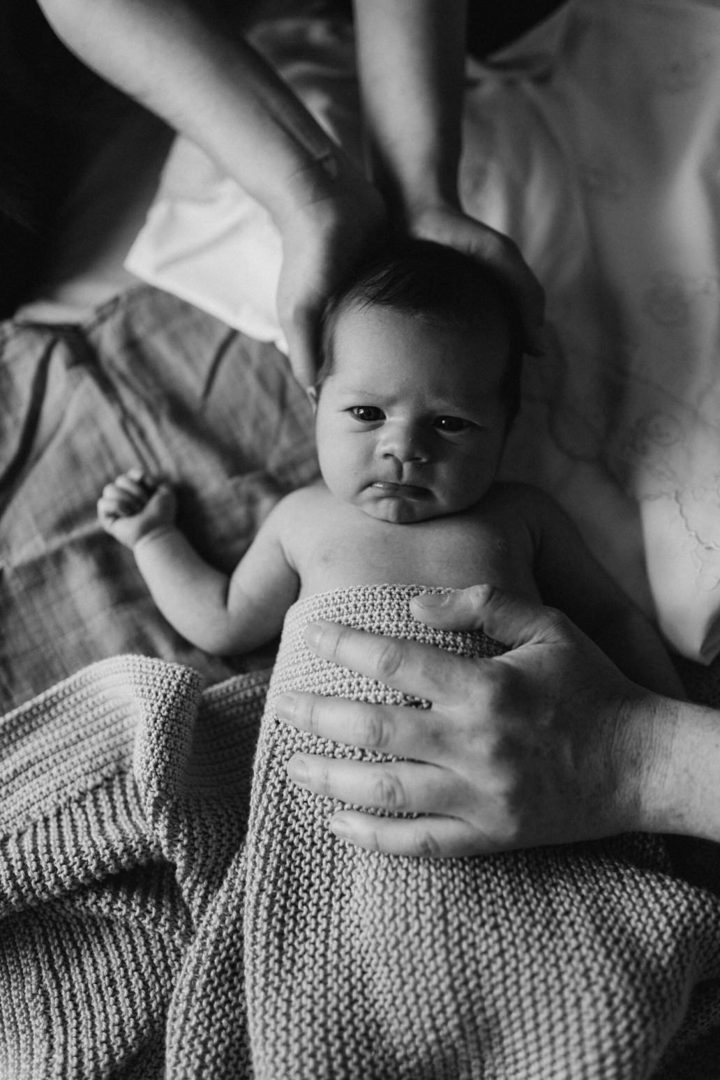 newborn baby wrapper up in a blanket and mom and dad's hands in Utrecht in a nice natural light