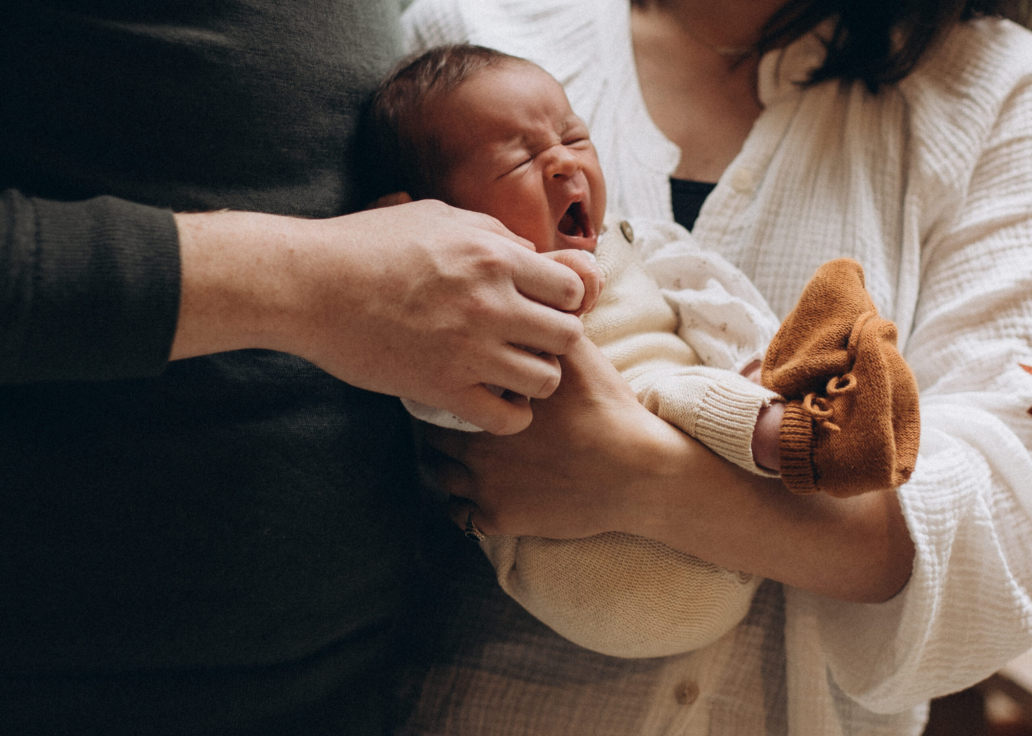 baby yawning in mom's arms in natural light in cozy family setting
