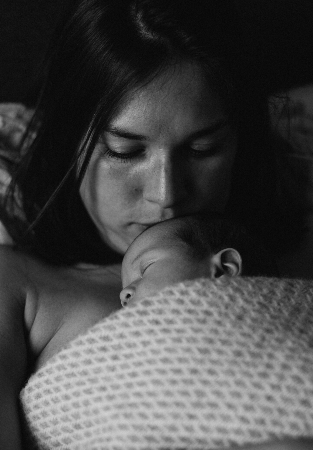 mom kissing baby forehead in black and white family home session in utrecht